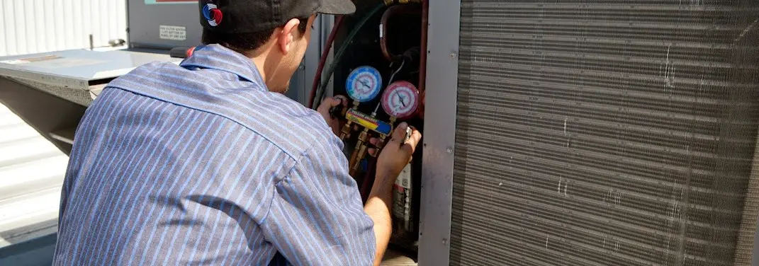 HVAC technician servicing a condenser unit in Stone Mountain